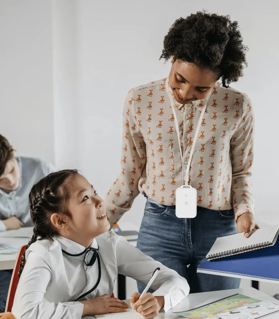 A K-12 teacher wearing a Punch Rescue emergency wearable panic button at a school in a classroom talking to a student.