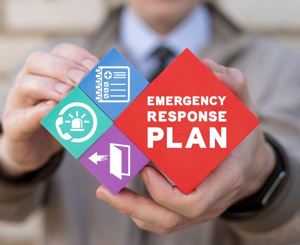 Hands holding colorful emergency response plan cards with icons for alert systems, checklists, and evacuation procedures in K-12 schools