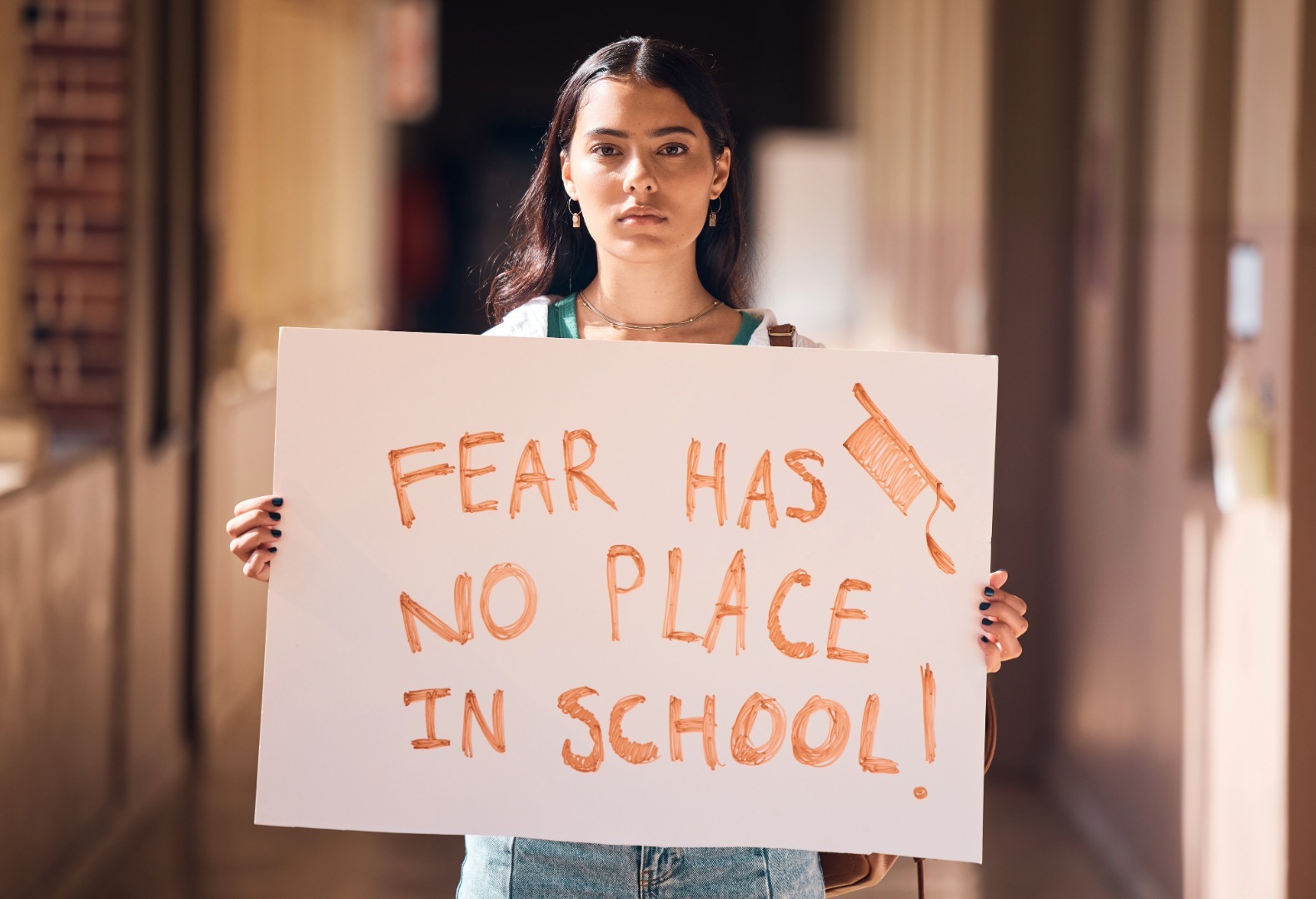 A student holding a sign to advocate for school safety infrastructure and emergency preparedness.