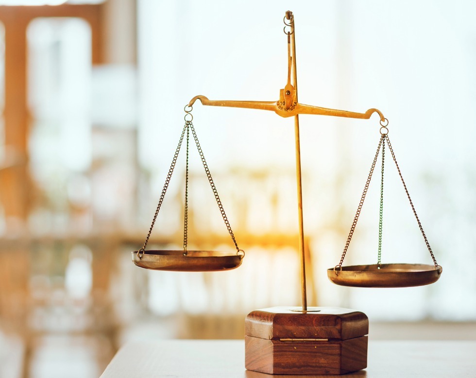 Golden balance scales representing the trade-offs between hardware-integrated and app-based school emergency communication systems